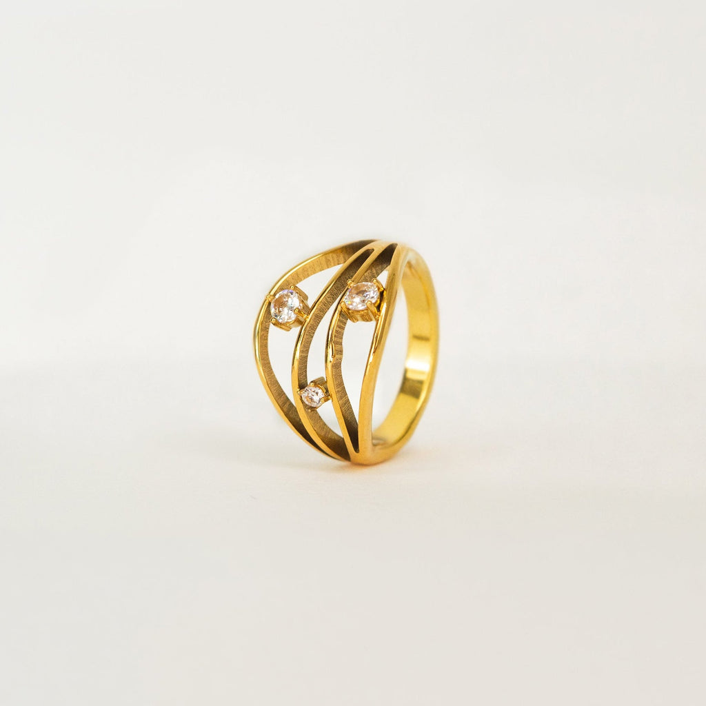 Gold ring with diamond accents on a light beige background