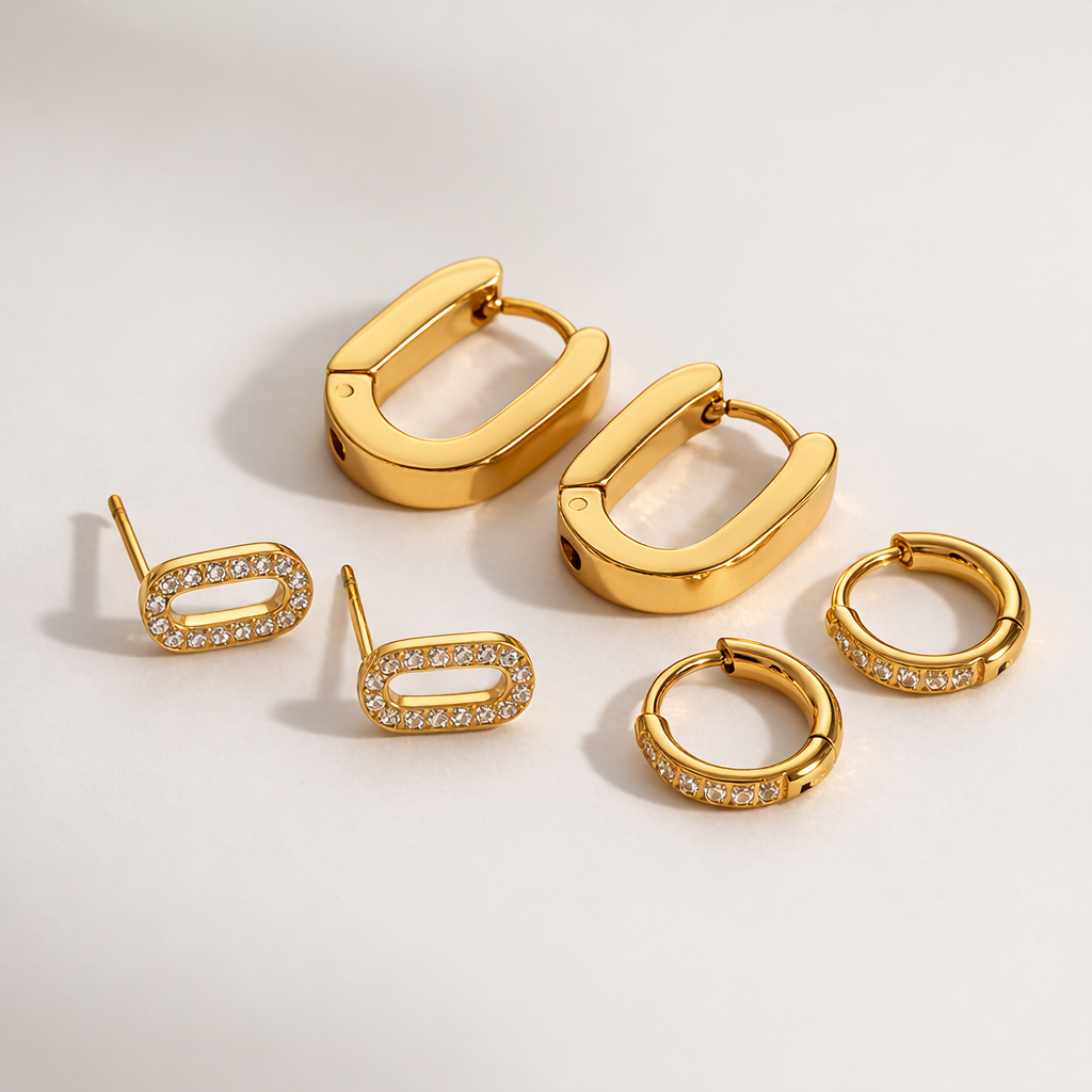 Set of gold hoop and stud earrings on a light background